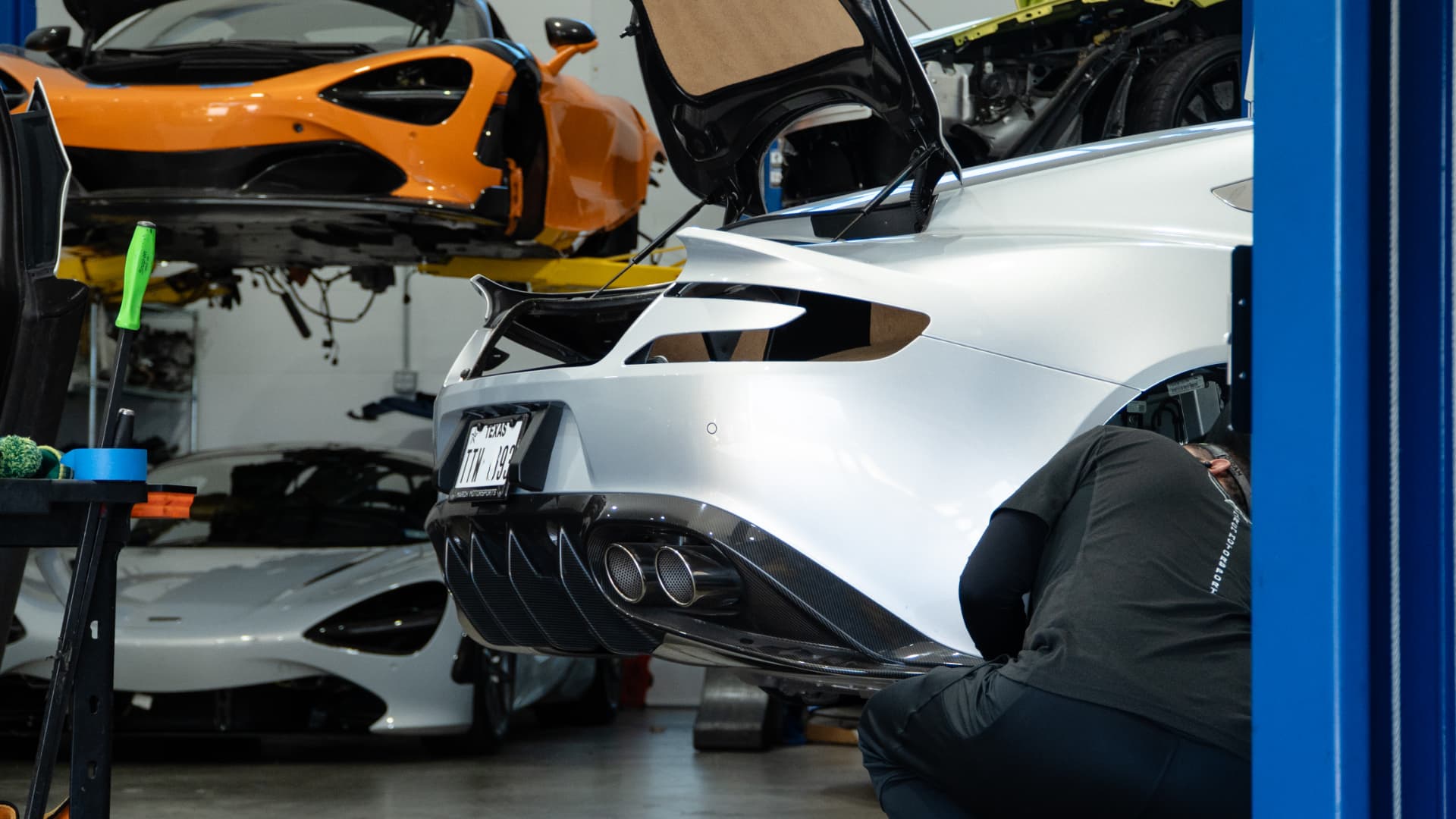 Technician working on the rear of a silver Aston Martin Vanquish on the lift at March Motorsports
