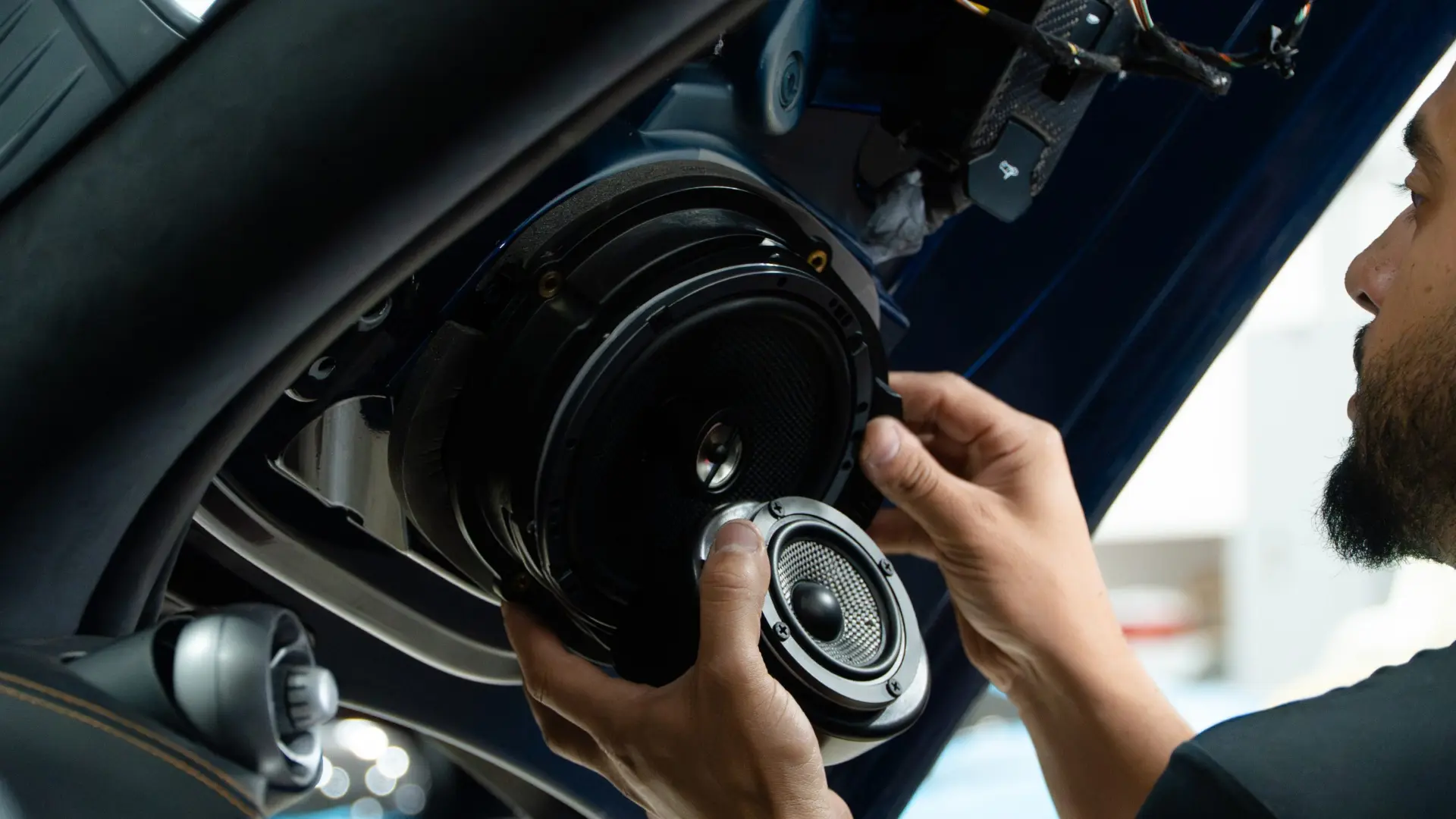 March Motorsports technician holding an upgraded speaker at the factory McLaren door aperture