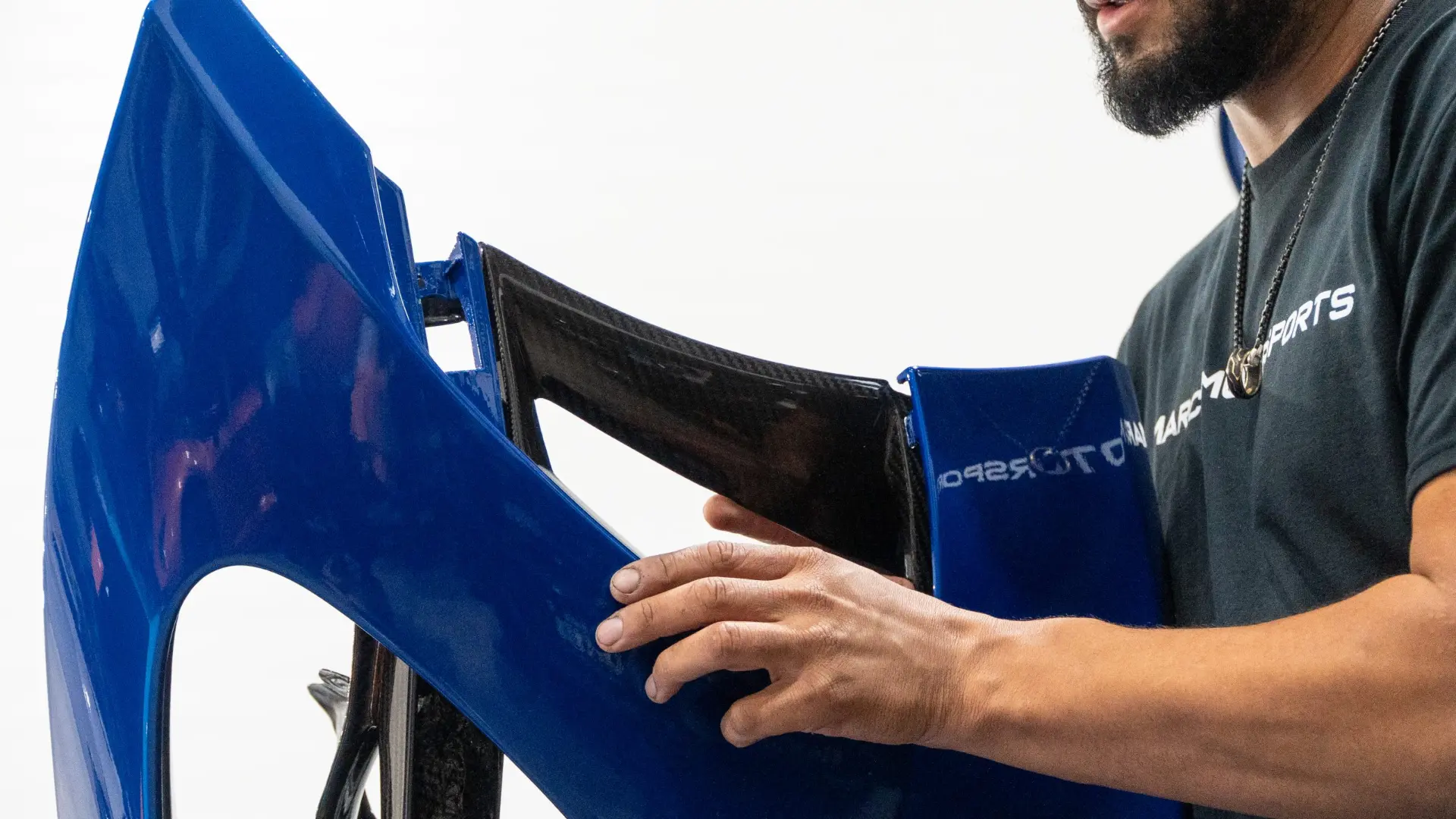 March Motorsports technician handling a blue McLaren body panel removed ahead of a wrap