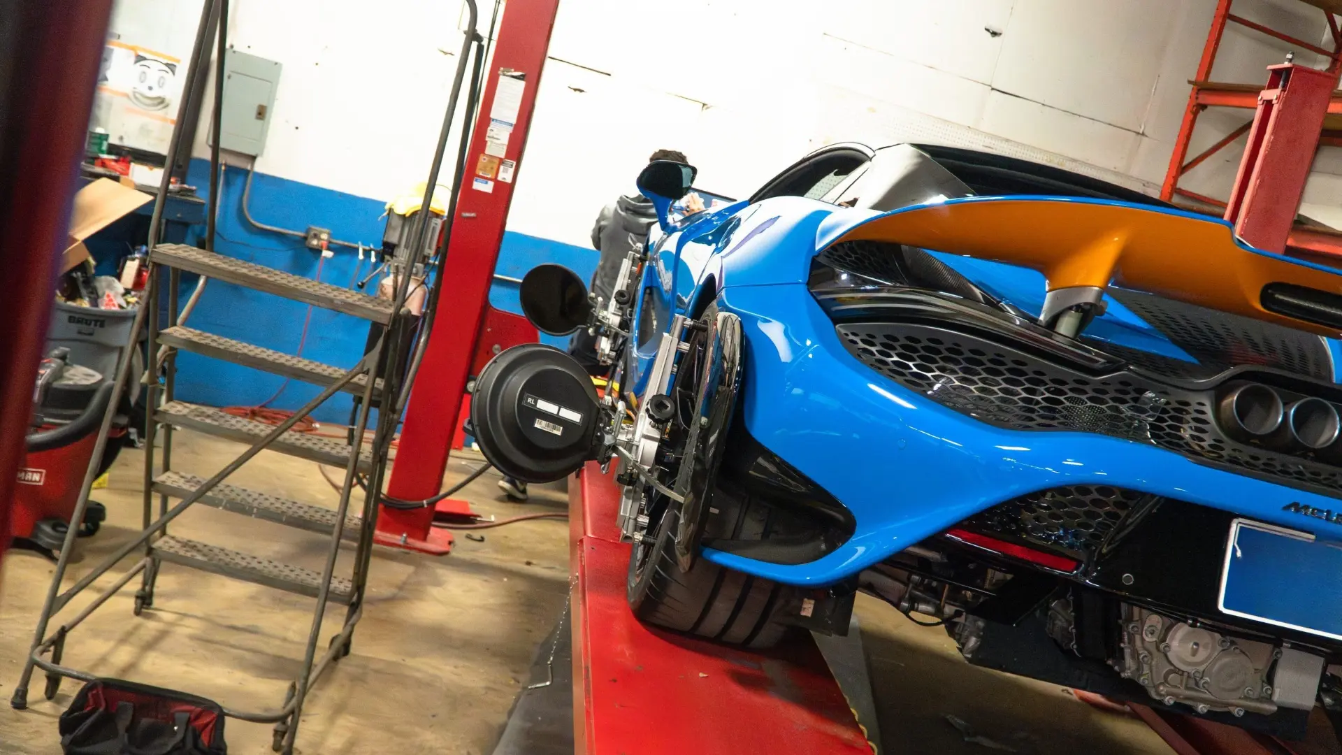 Blue McLaren 720S Spider on the lift with a laser alignment head on its rear wheel at March Motorsports