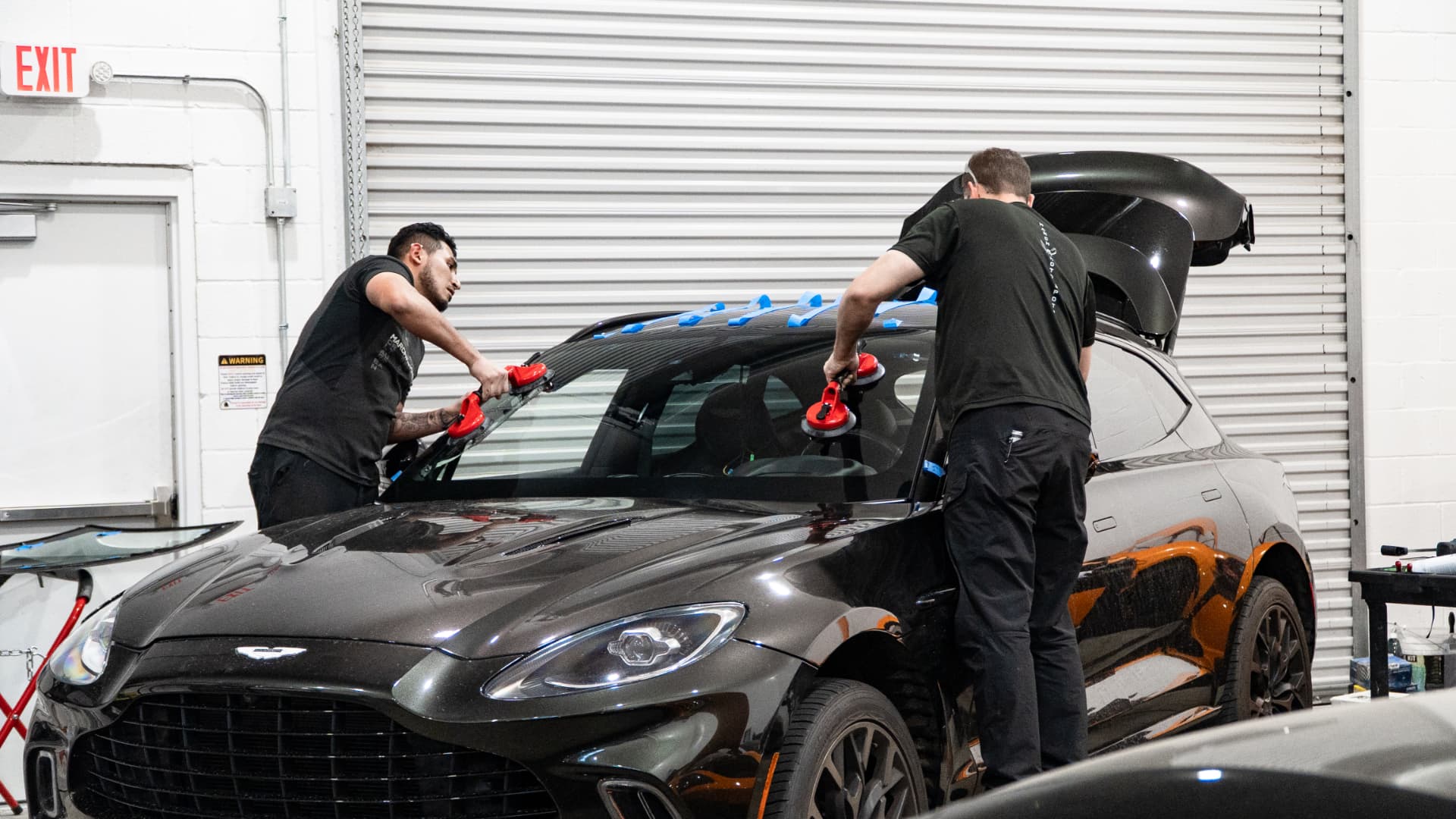Technicians fitting a new windshield on an Aston Martin DBX
