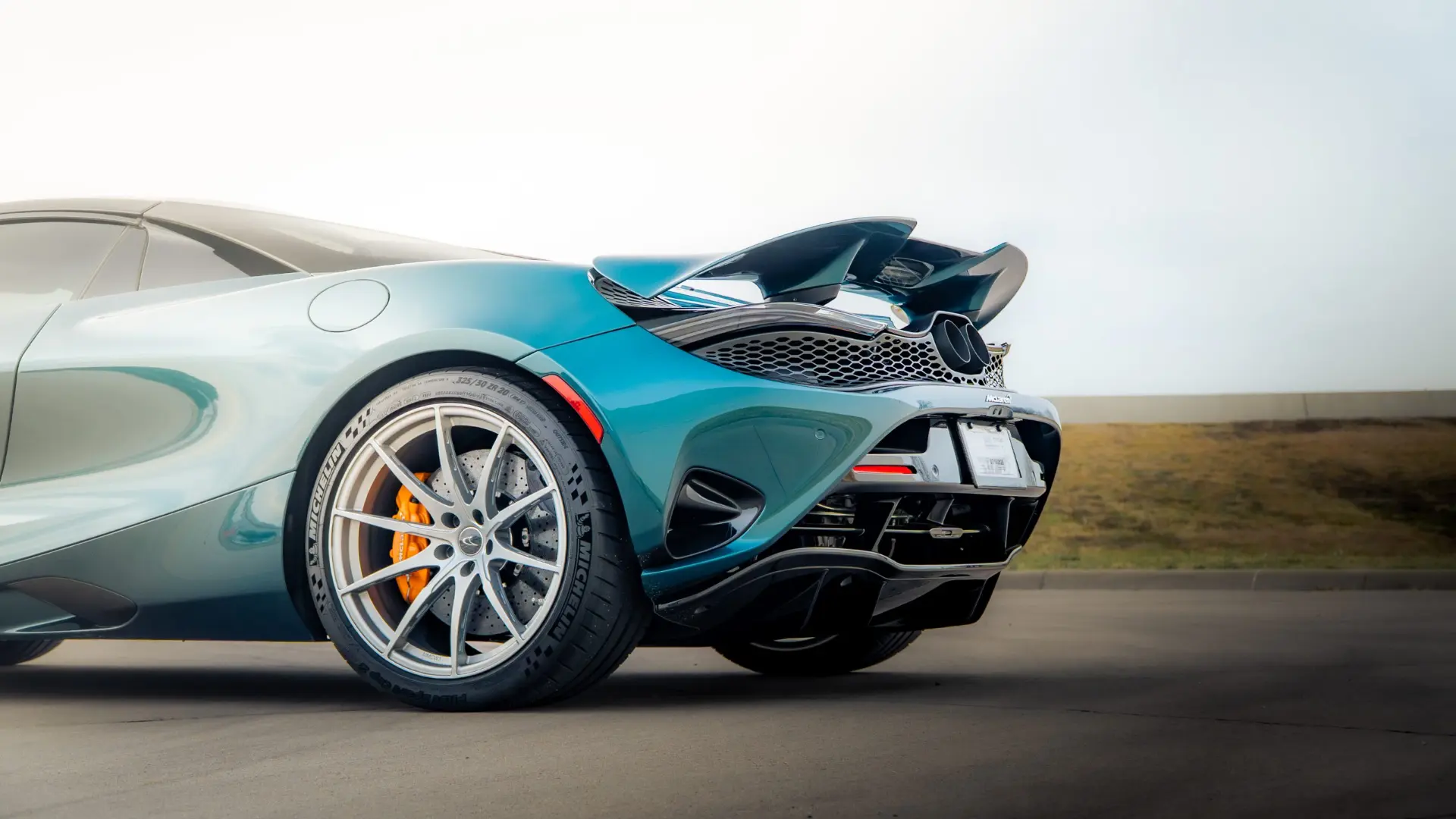 Teal McLaren 765LT rear quarter with silver wheel and orange caliper at March Motorsports in Carrollton, Texas