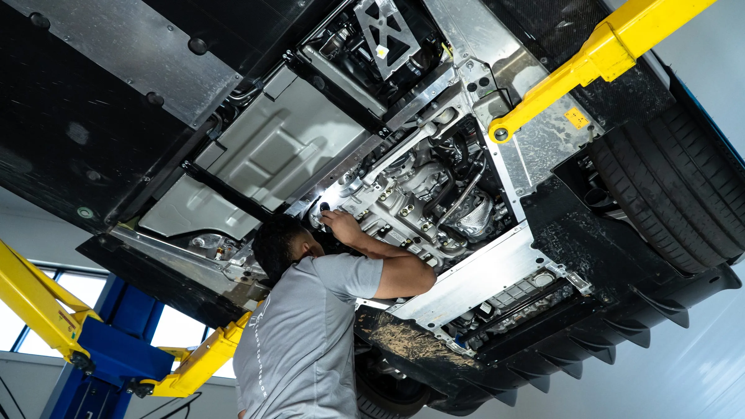 March Motorsports technician inspecting the underbody of a McLaren on the lift