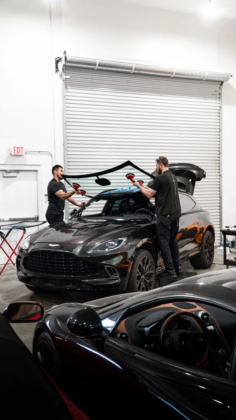 Two technicians fitting a windshield on an Aston Martin DBX at March Motorsports