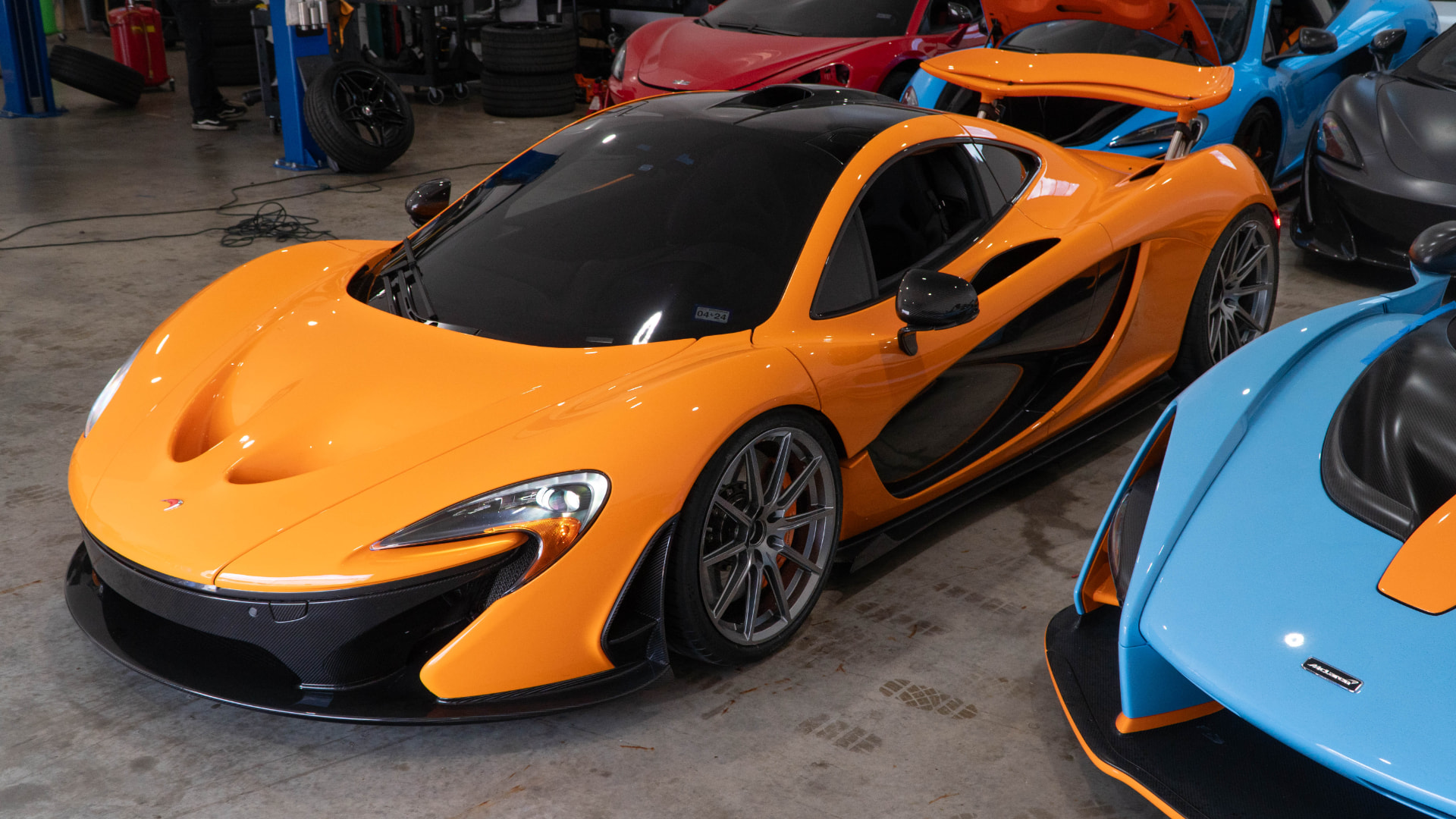 Orange McLaren P1 front three-quarter in the March Motorsports workshop among other McLarens