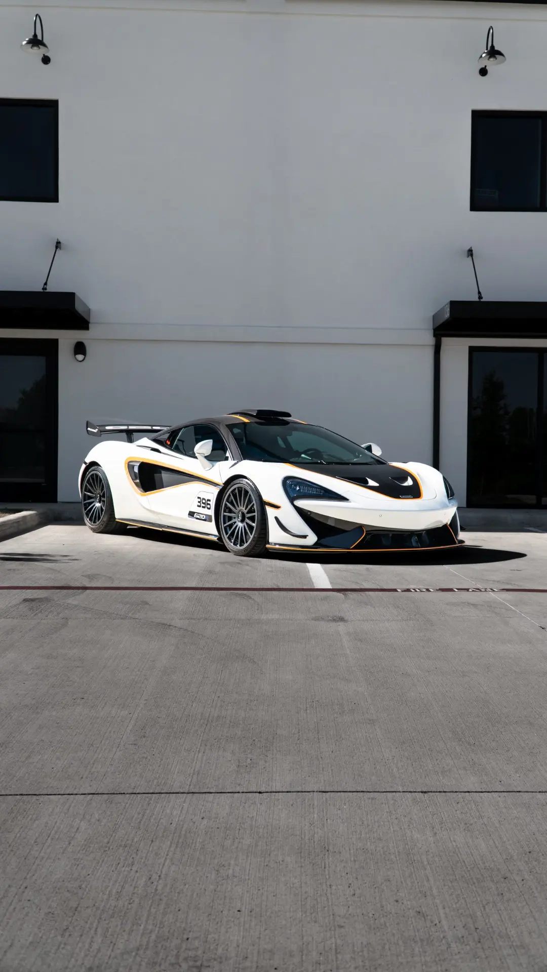 White McLaren 570S with papaya accent graphics and race numbering outside the March Motorsports studio