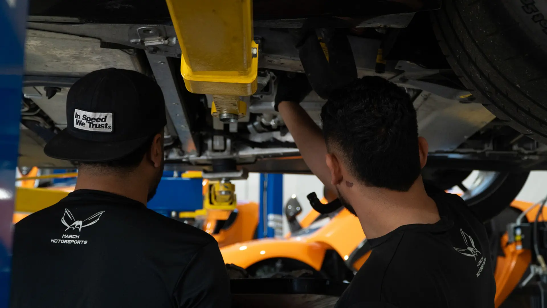 Technicians inspecting a McLaren underbody on the lift