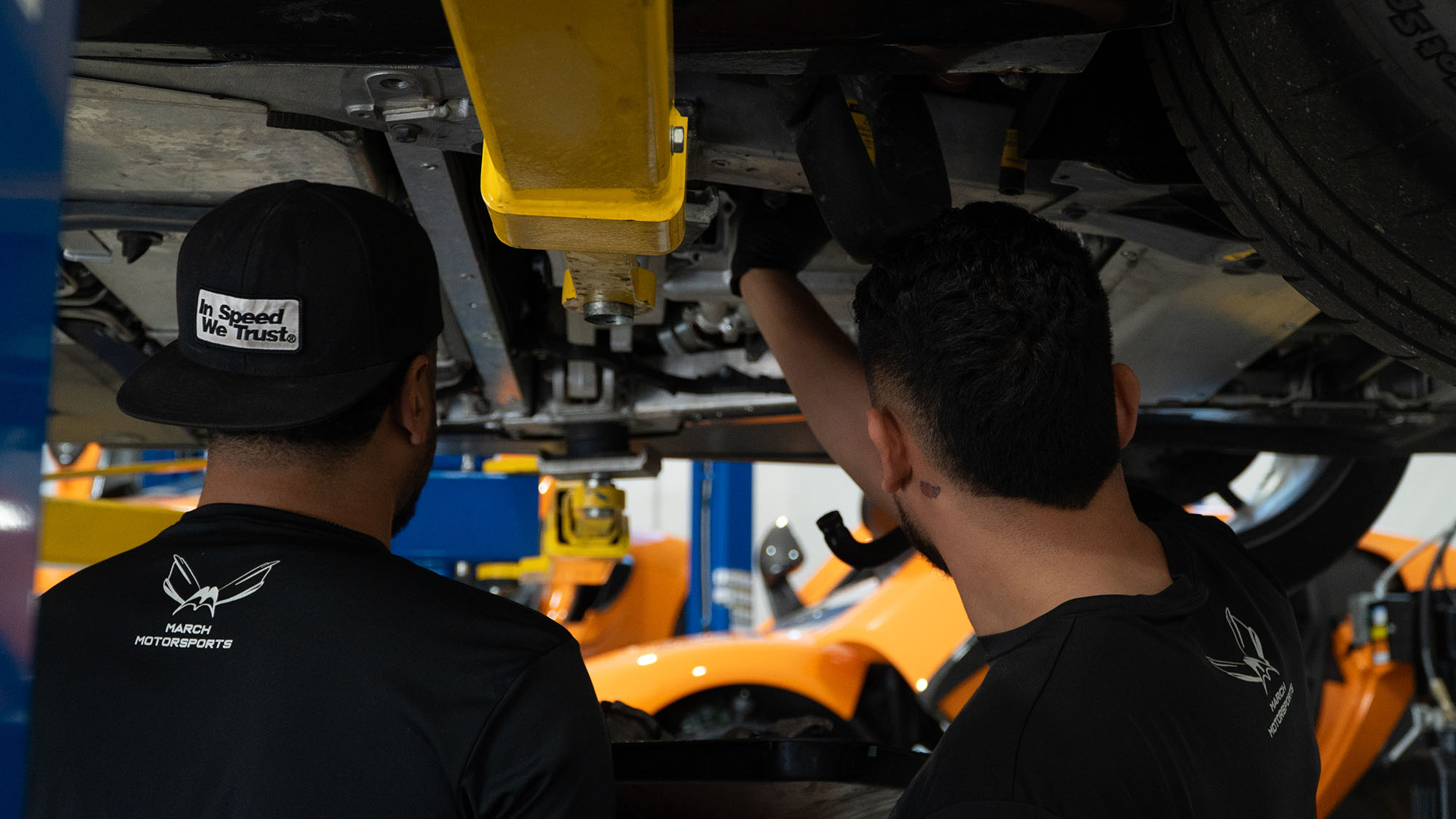 Two technicians inspecting a McLaren underbody together