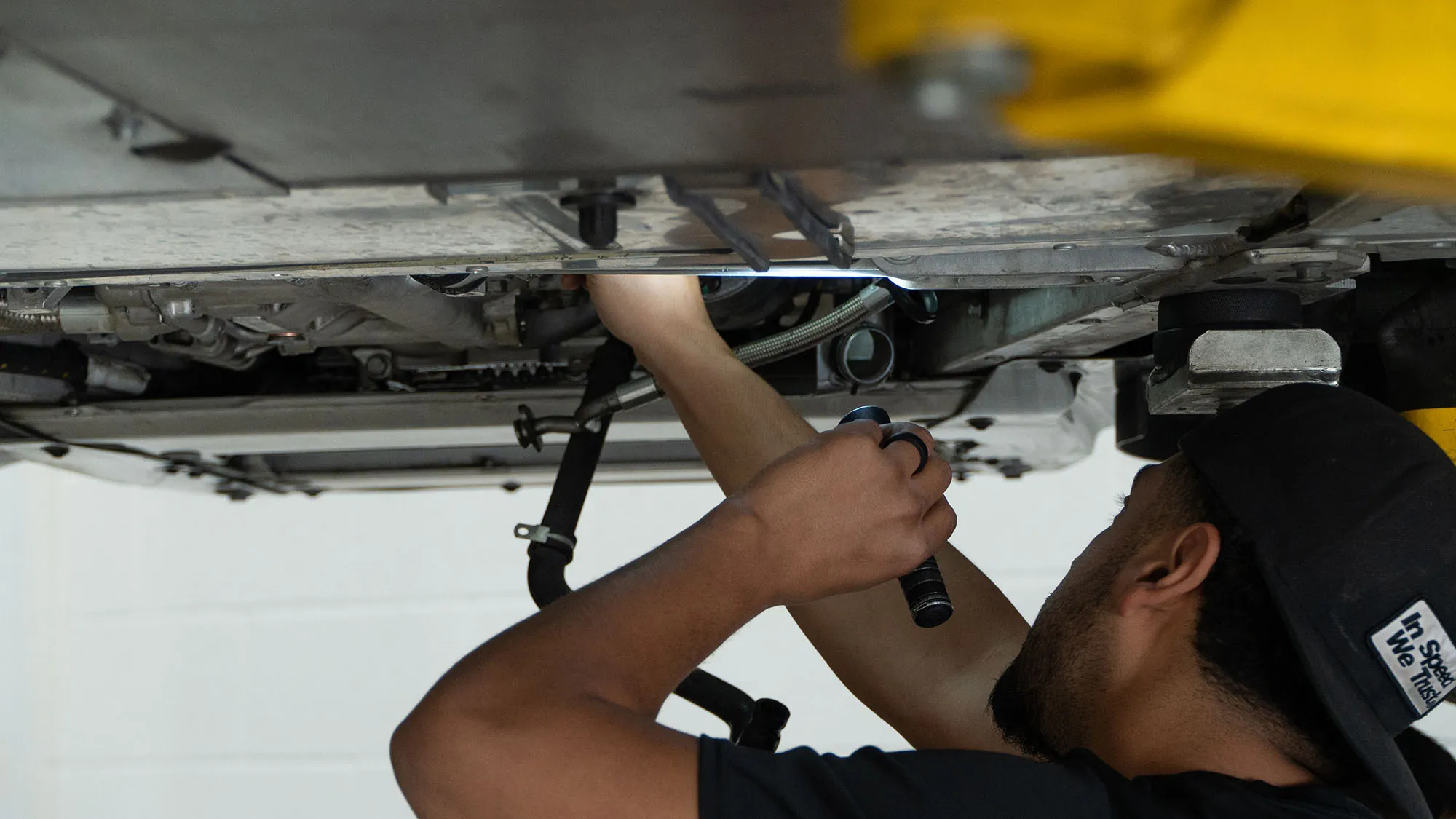 A March Motorsports technician inspecting the underside of a McLaren from below on the lift