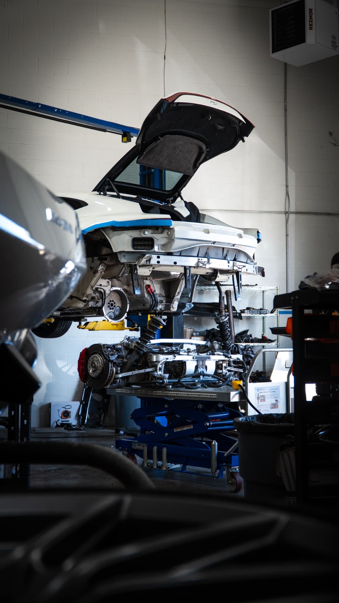 Aston Martin Vantage on the lift at March Motorsports with its rear suspension and drivetrain disassembled