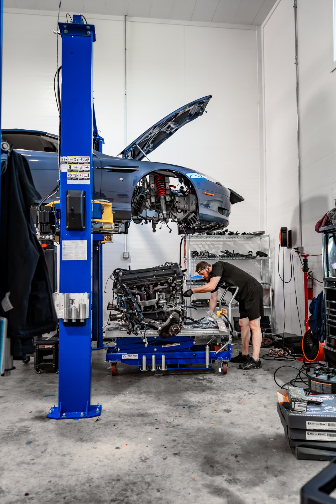 Aston Martin DB9 on the lift at March Motorsports with its engine removed on a cart below