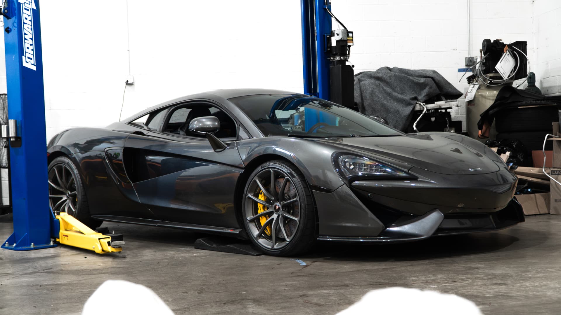 Grey McLaren 570S between the lift posts in the March Motorsports workshop