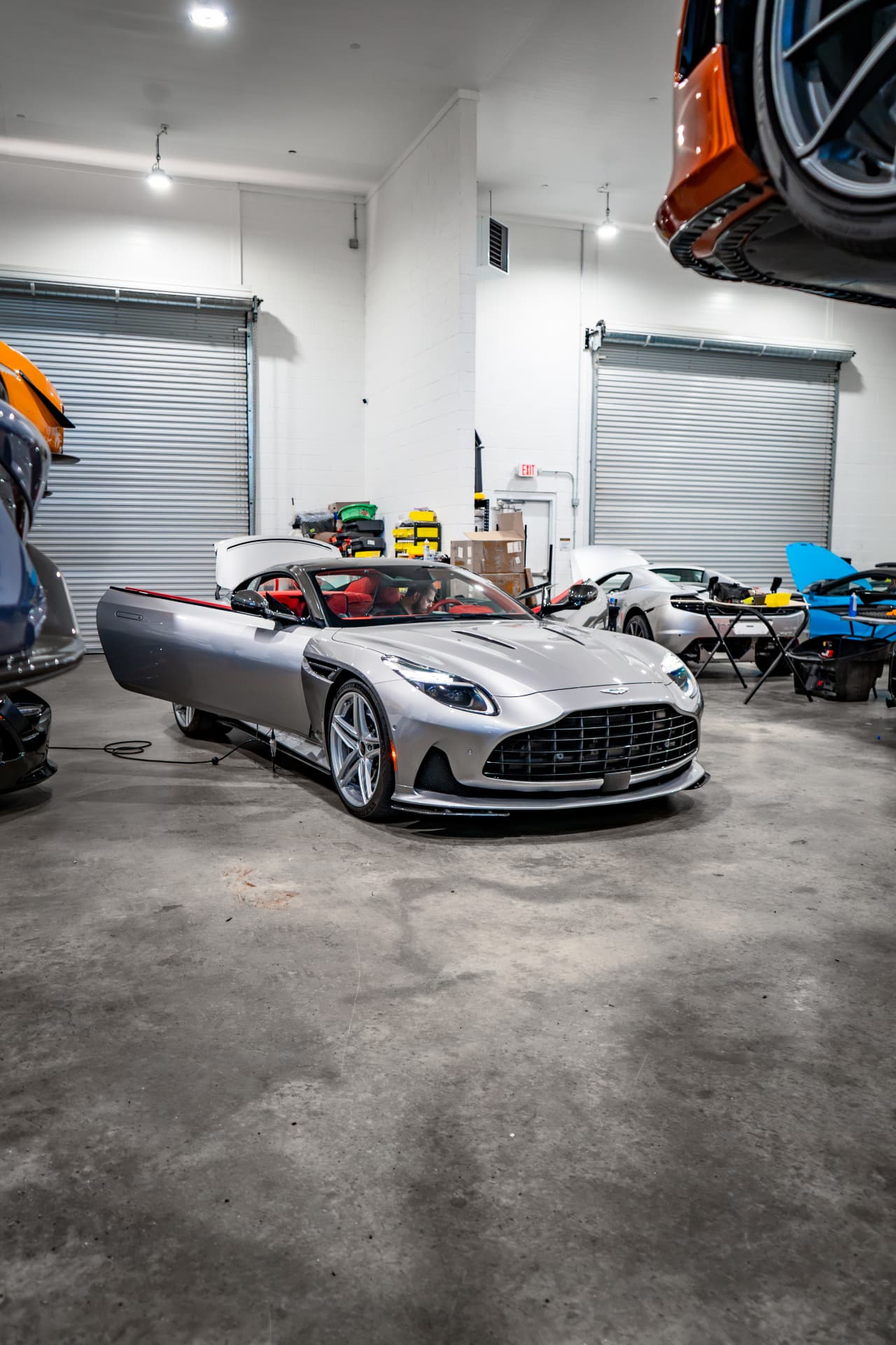Silver Aston Martin DB12 with its doors open in the March Motorsports workshop