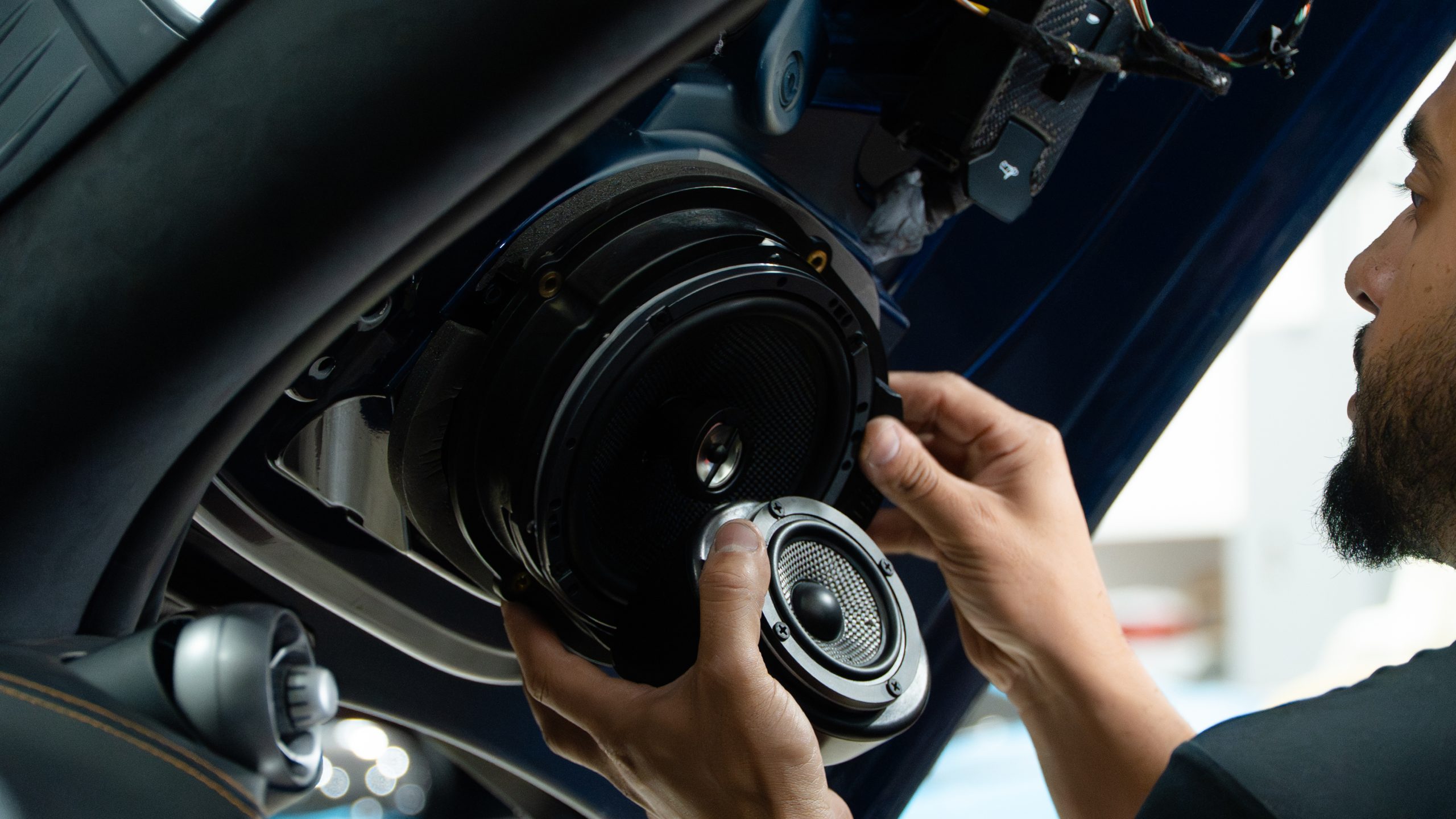Technician fitting an upgraded mid driver where the thin stock McLaren speaker sat