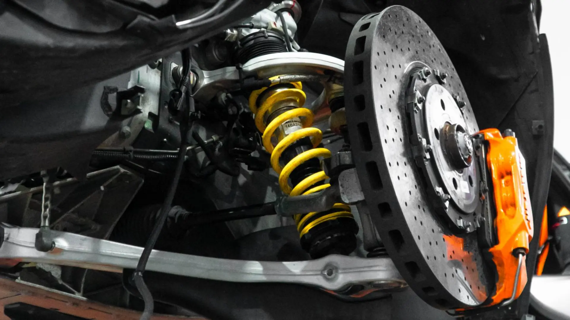 McLaren coilover suspension and drilled carbon ceramic disc with an orange brake caliper on the lift at March Motorsports