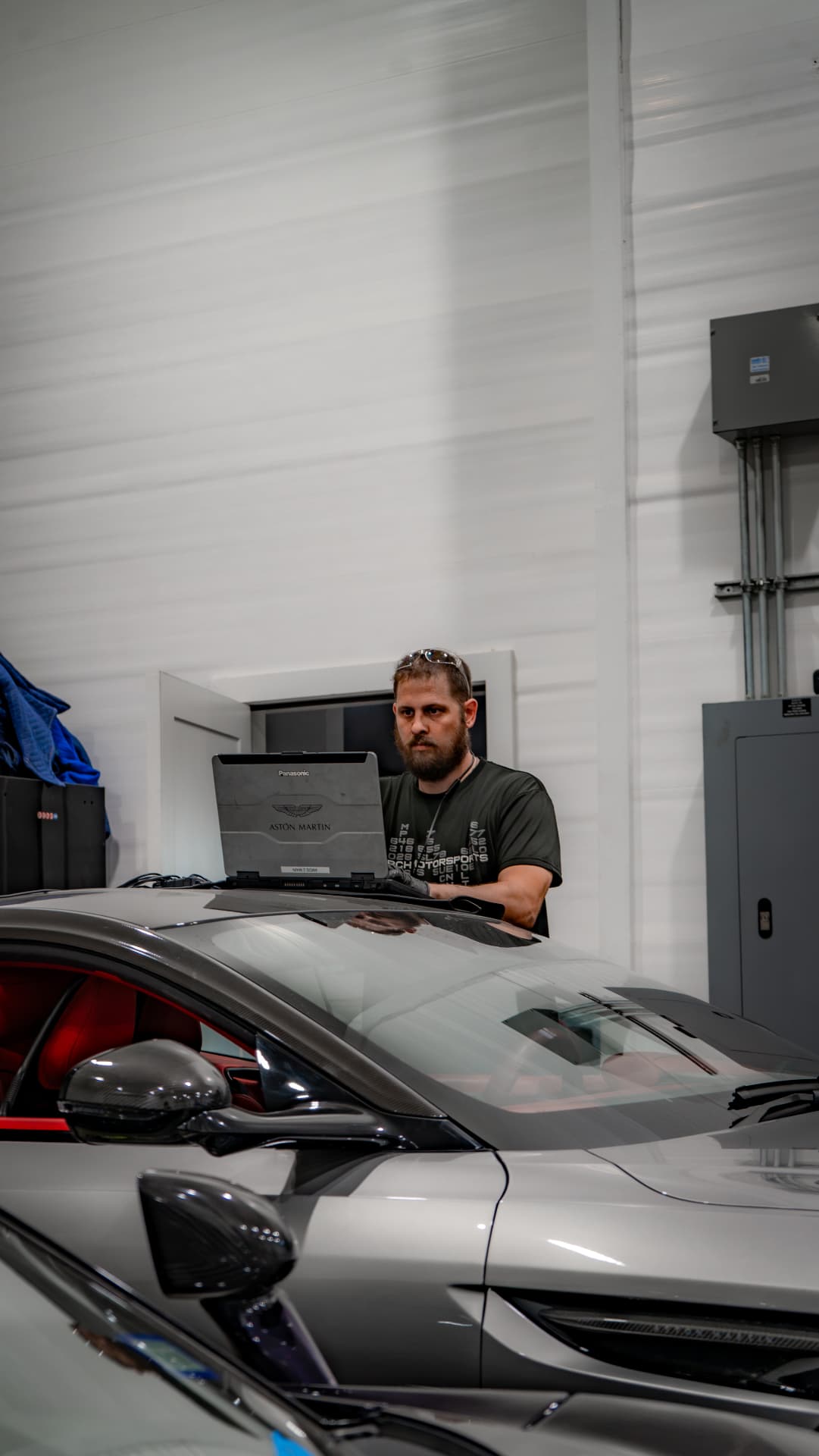 Technician running Aston Martin diagnostics on a silver DB12 at March Motorsports in Carrollton