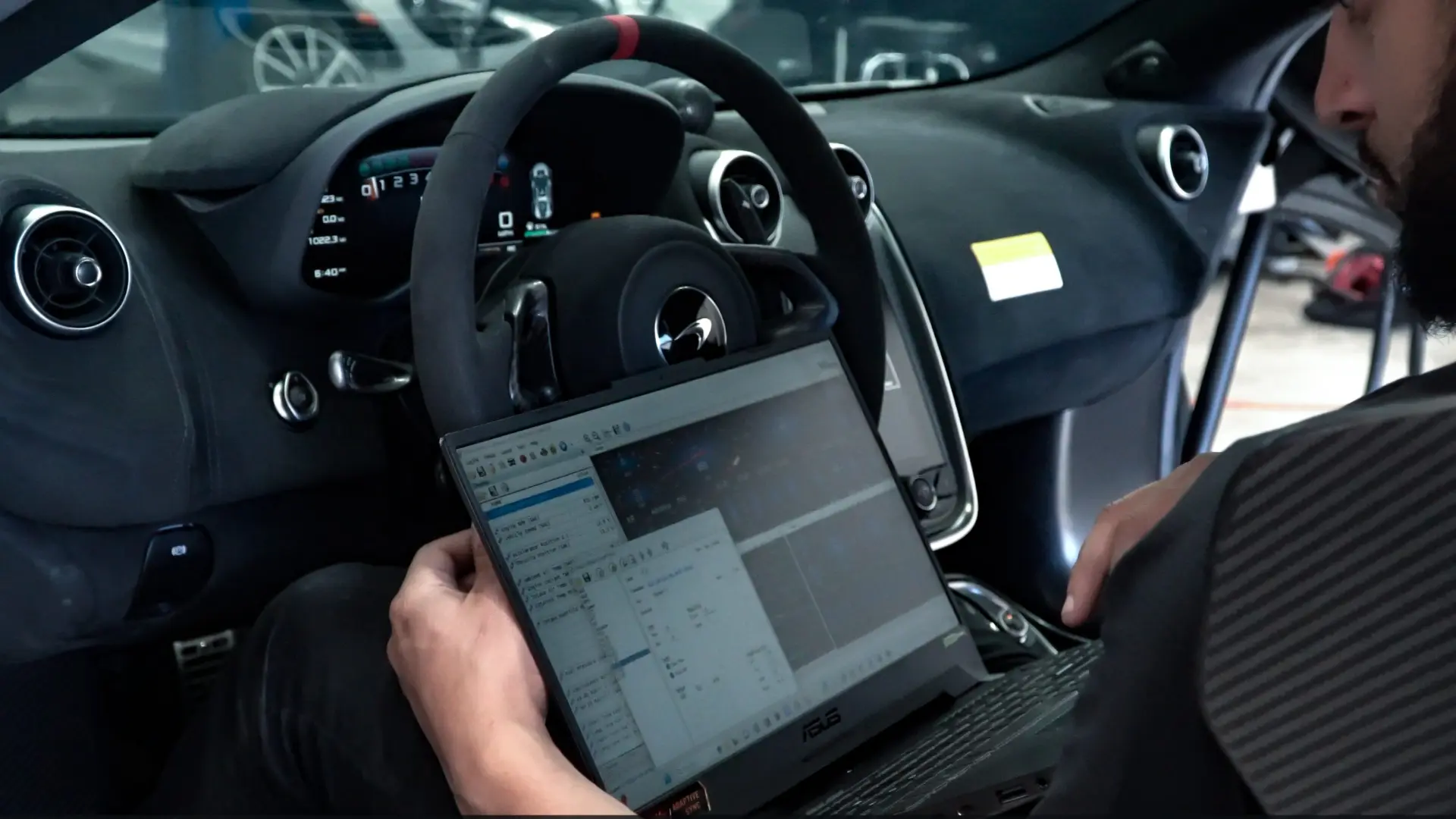 Technician running a calibration laptop inside a McLaren cabin at March Motorsports