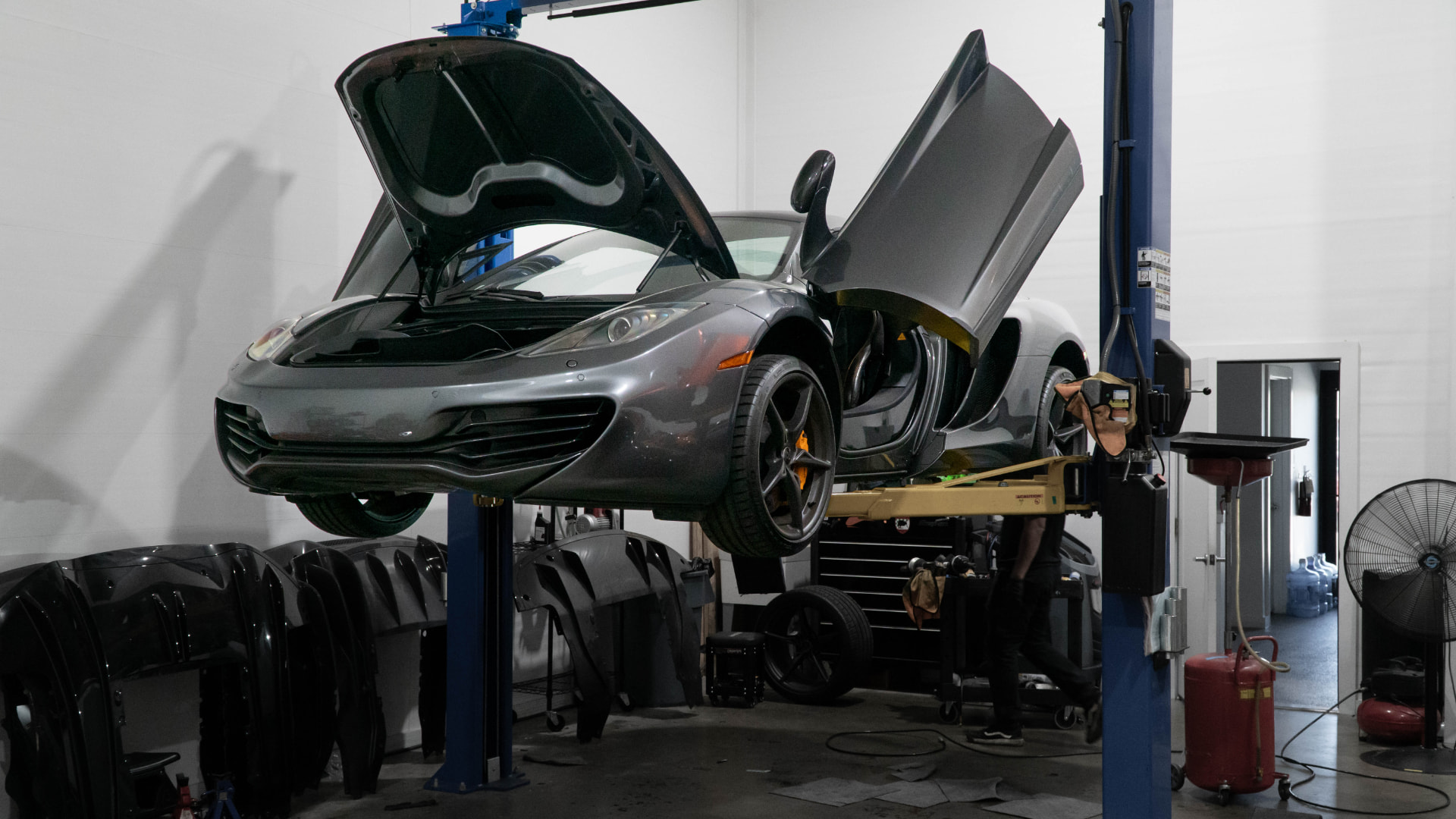 Grey McLaren MP4-12C on the lift with its front trunk and dihedral door open at March Motorsports