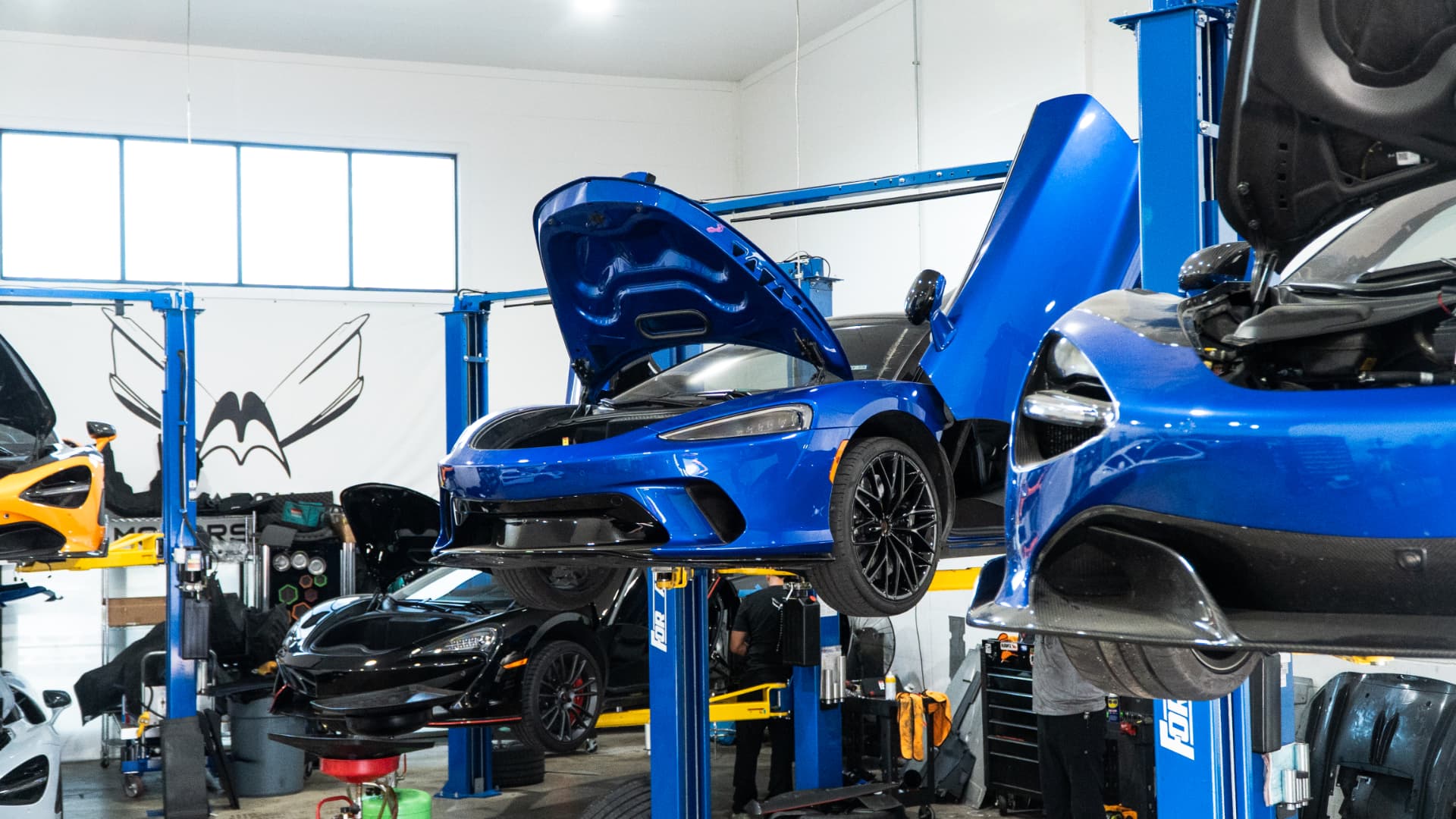 Blue McLaren GT on the lift in the March Motorsports workshop with its door and rear deck open