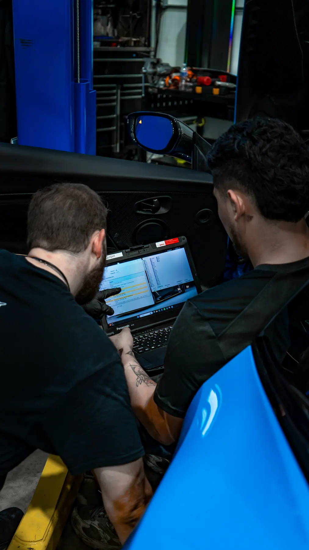 Technicians running the Aston Martin AMDS diagnostic system on a DBS