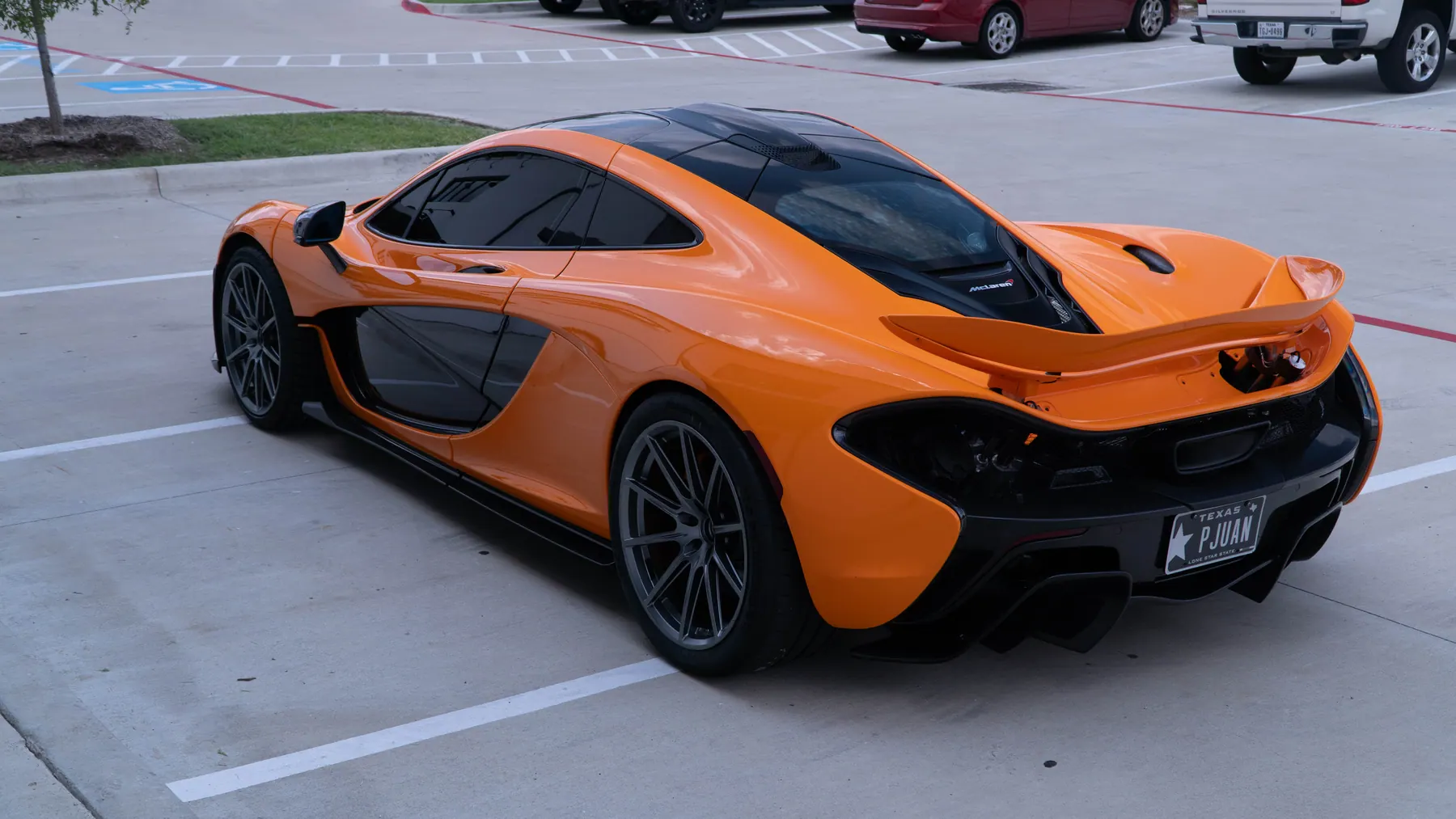 Orange McLaren P1 rear three-quarter view outside March Motorsports, showing the high-mounted exhaust outlet